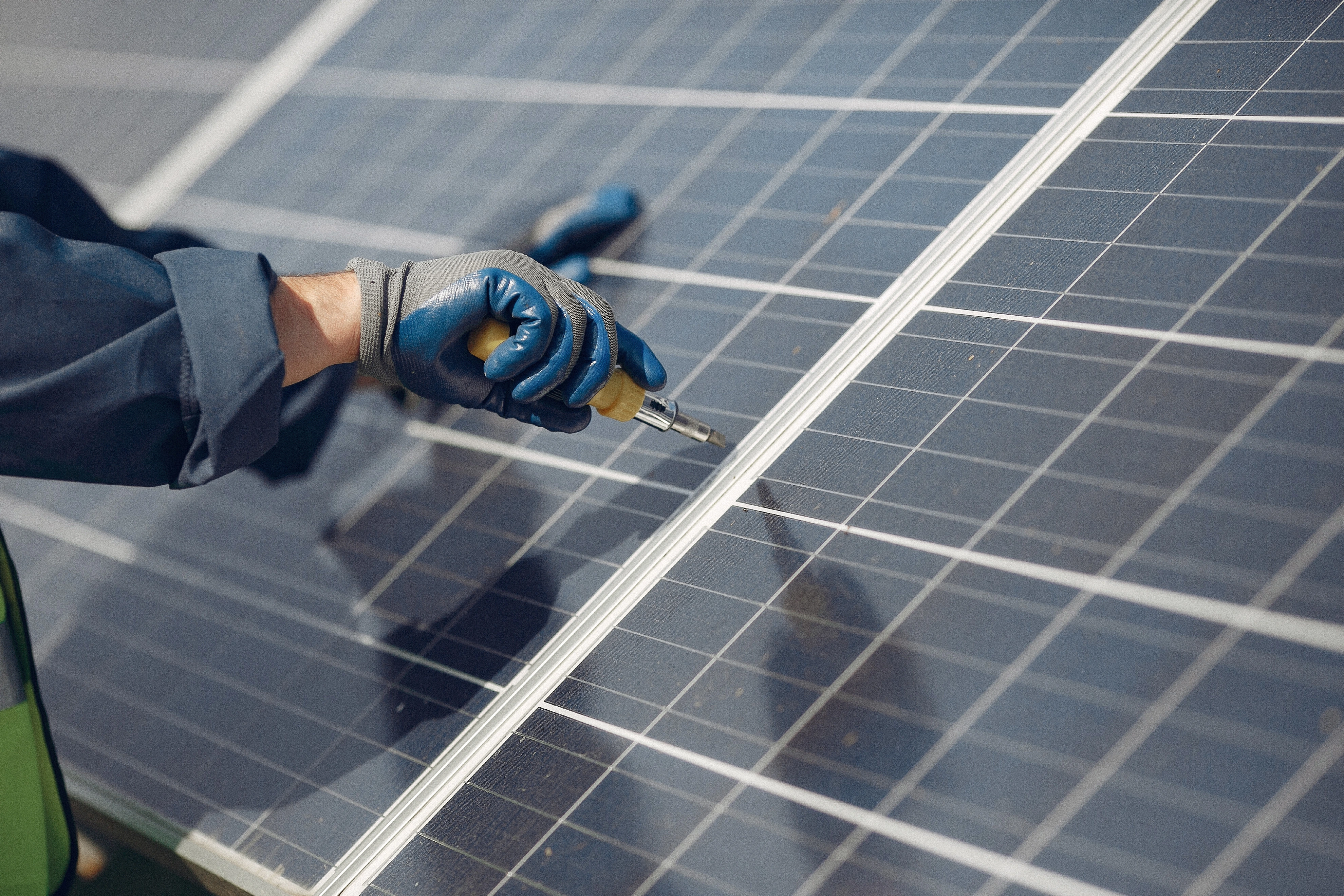 man with white helmet near solar panel