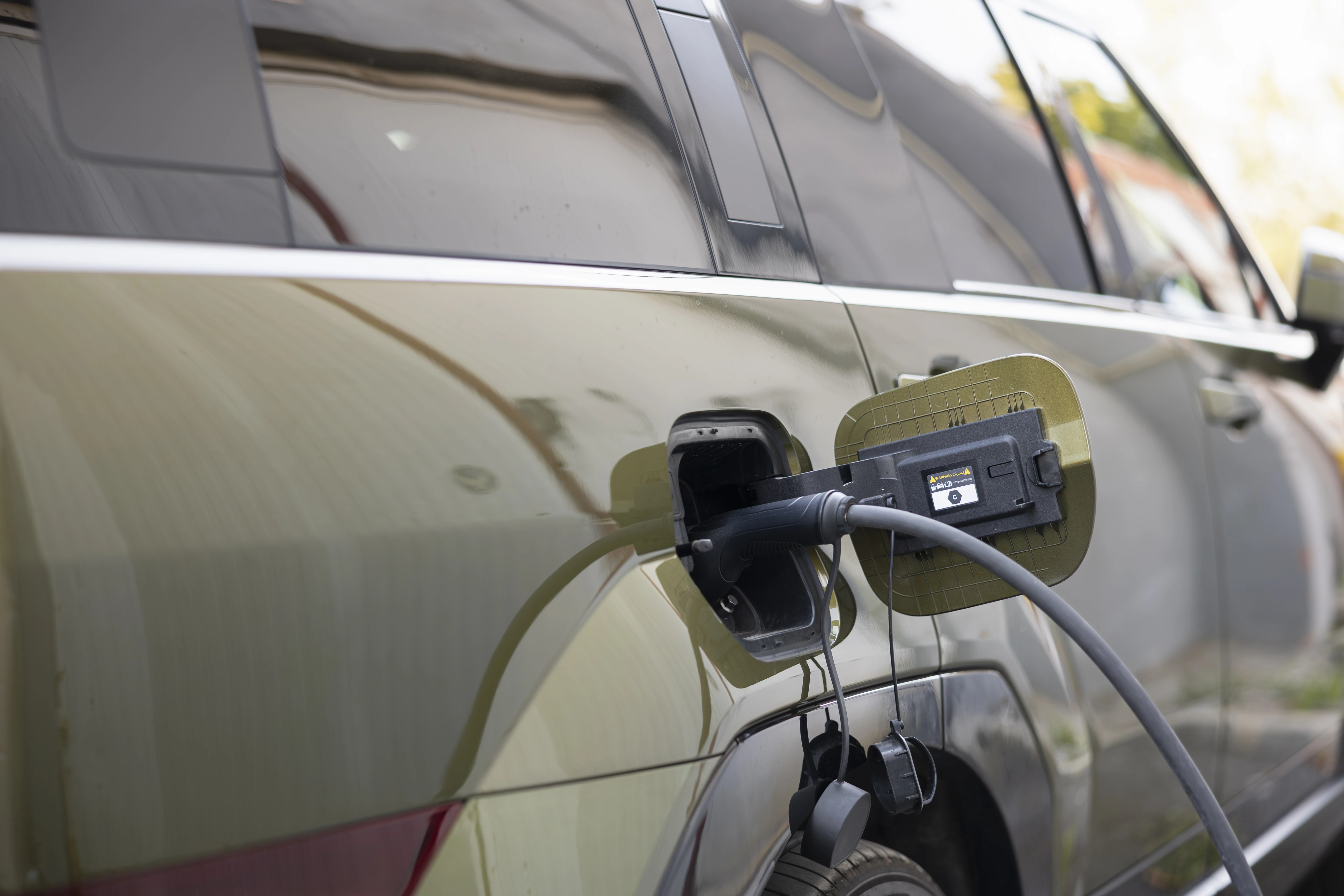 Close-up of an EV plug connected to a car during home charging installation.