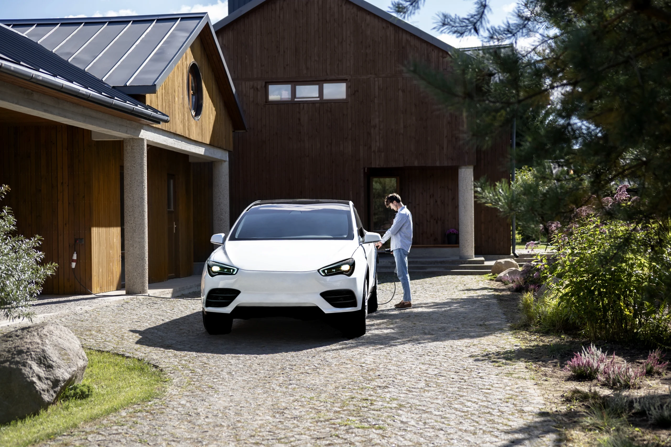 Person connecting an EV to a home charging point, reflecting the need for two chargers when charging multiple electric vehicles.
