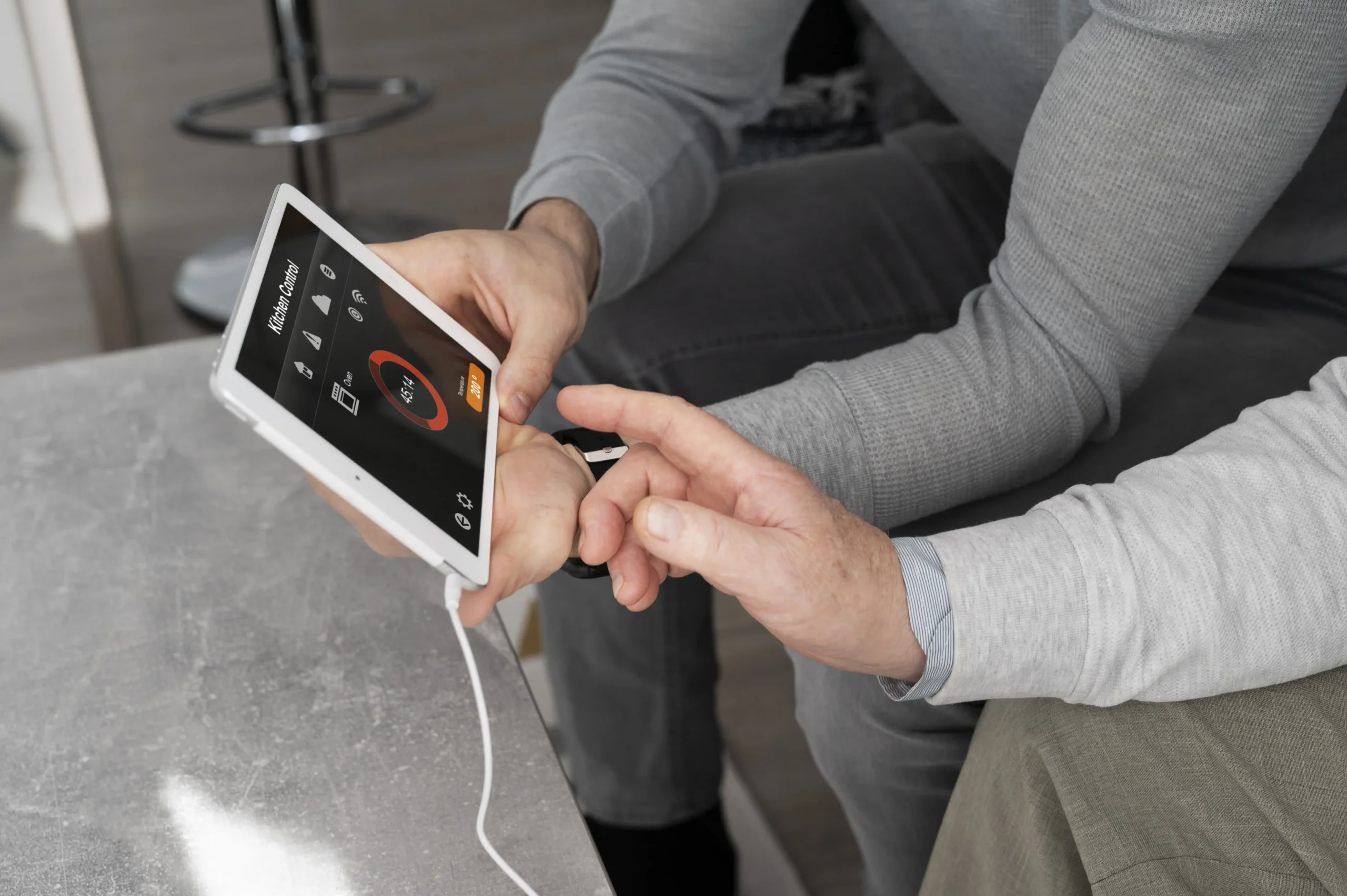 Two people reviewing a tablet showing a home energy control interface, illustrating how a HEMS provides real-time energy management.