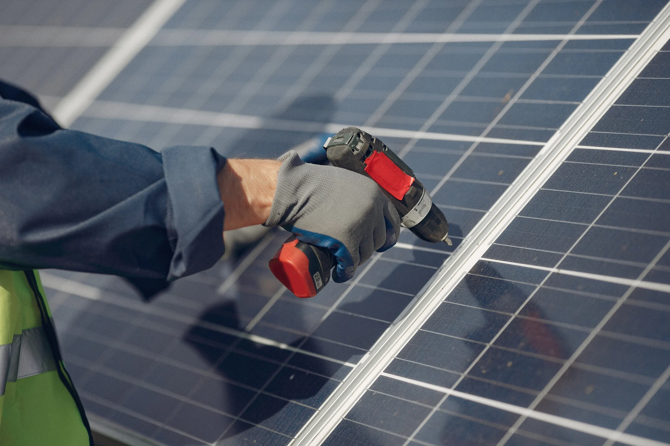 Installer using a power tool to secure a solar panel during setup, representing part of a homeâ€™s integrated energy system.