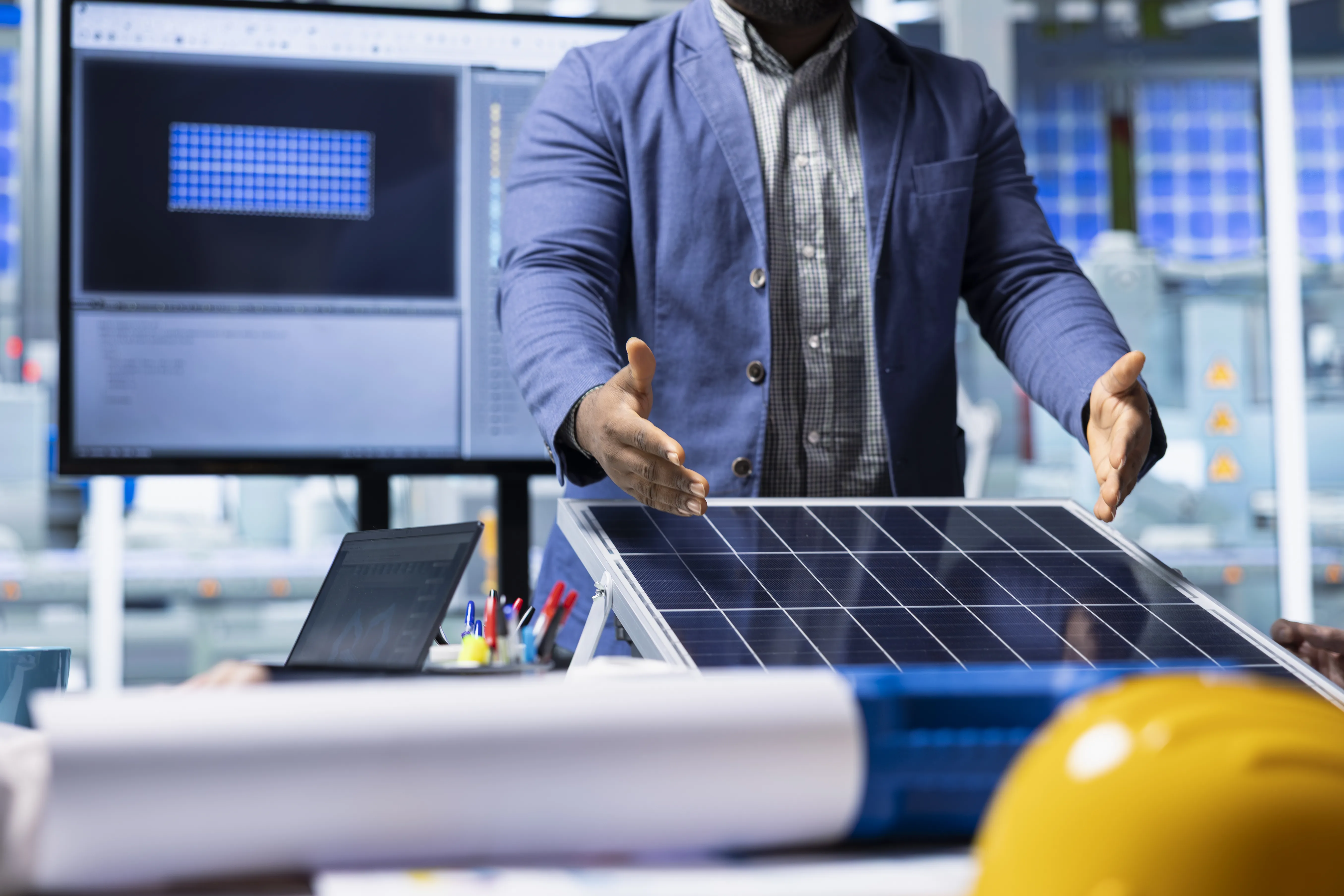 Person demonstrating a solar panel in a workspace with analysis software, representing how solar technology is tested and improved.