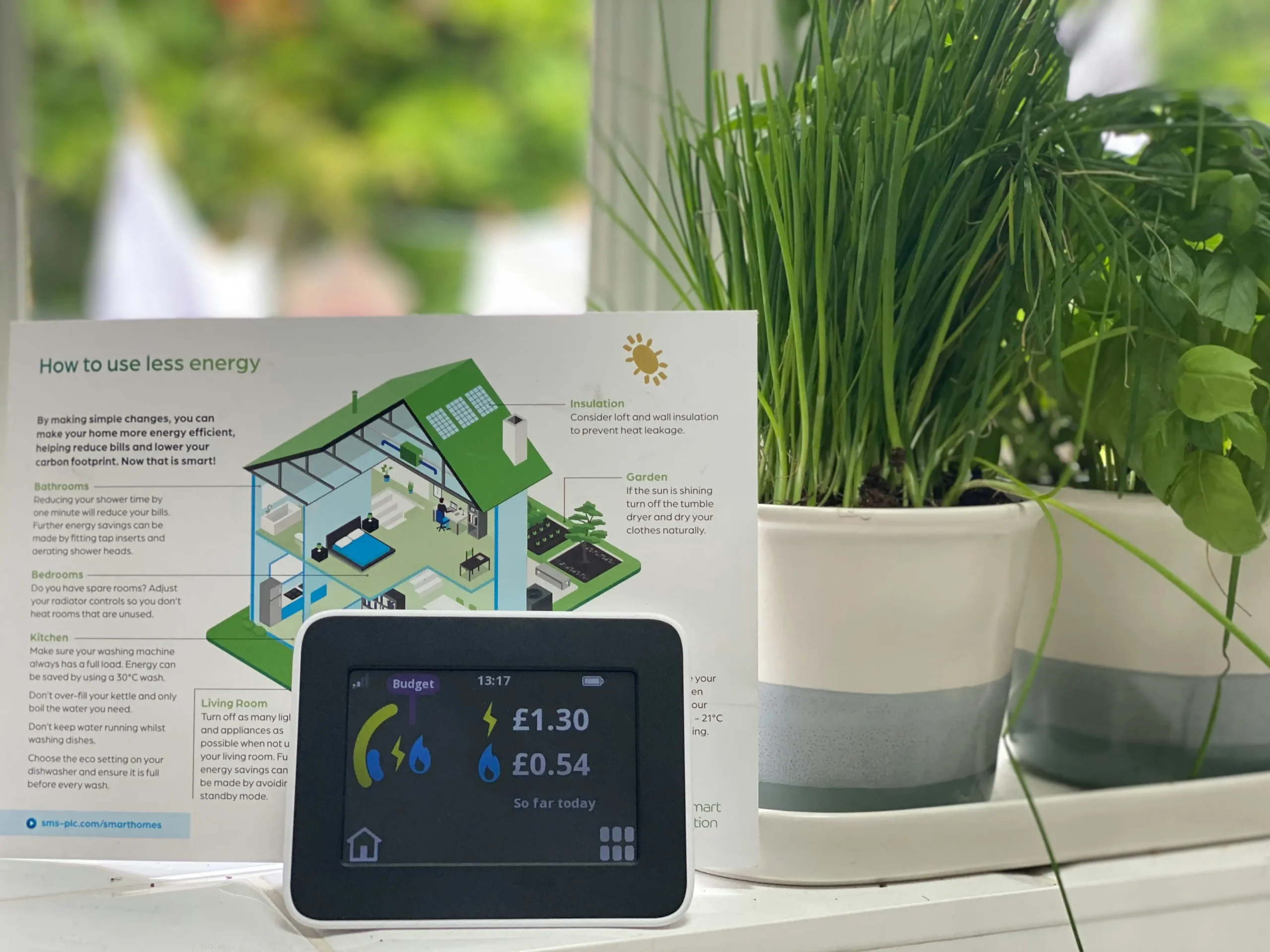 Smart meter display showing electricity and gas usage costs for the day, beside a guide to reducing energy use, illustrating how homes track data for time-of-use tariffs.