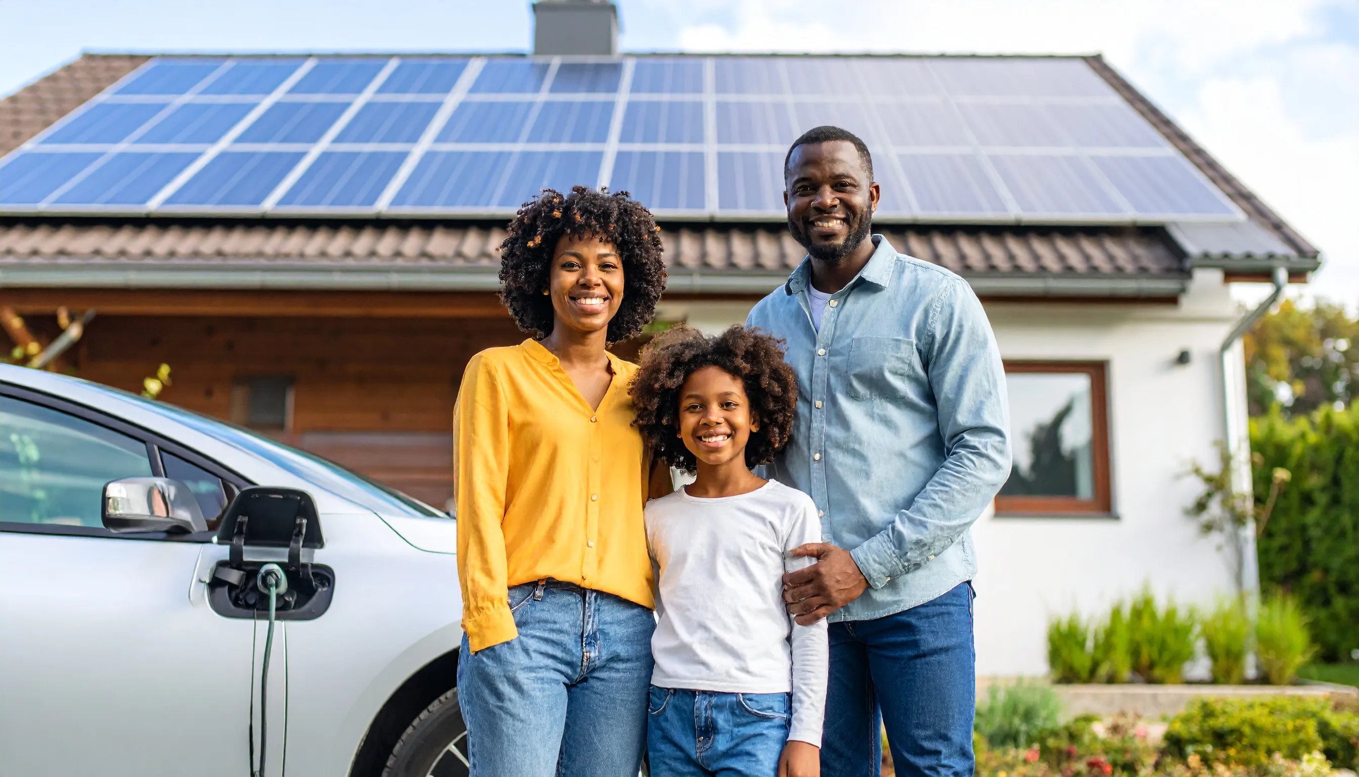 A family standing outside their home with rooftop solar panels and an electric car, illustrating how new solar technologies benefit modern UK households.