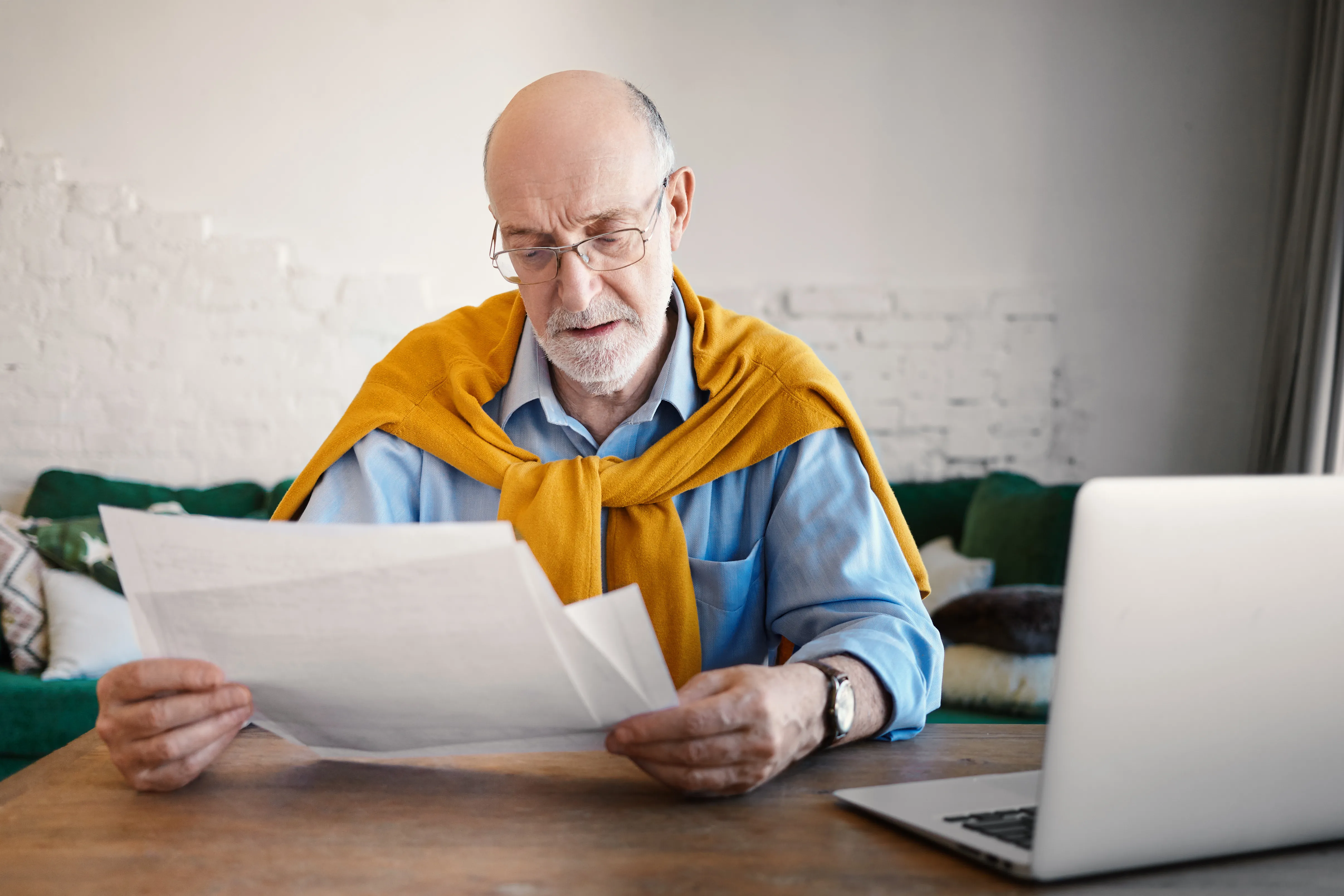 Senior man studying his household bills to try to understand his rising electricity prices.