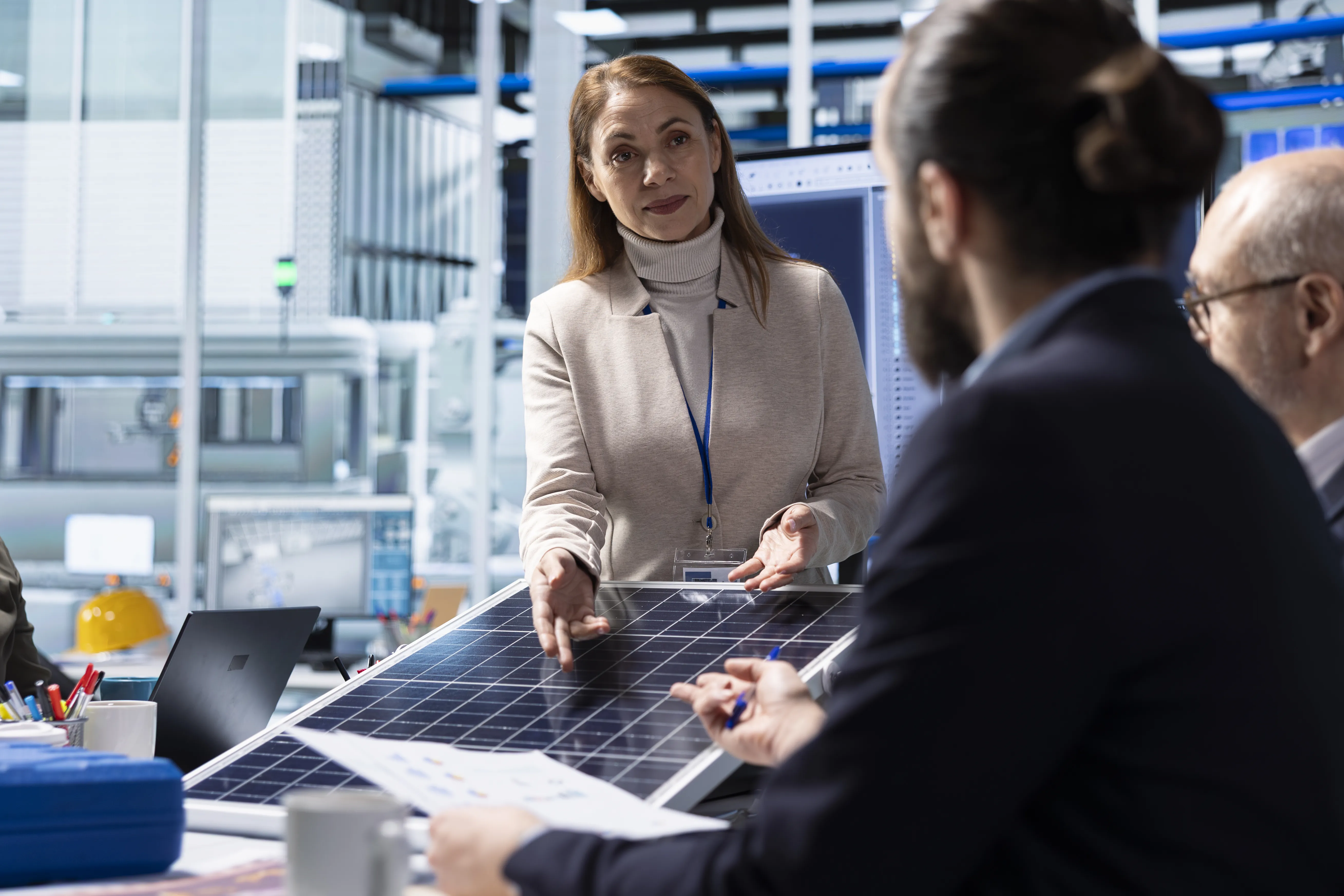 Business professionals discussing a solar panel installation and reviewing data, illustrating evaluation of solar investment for commercial use.