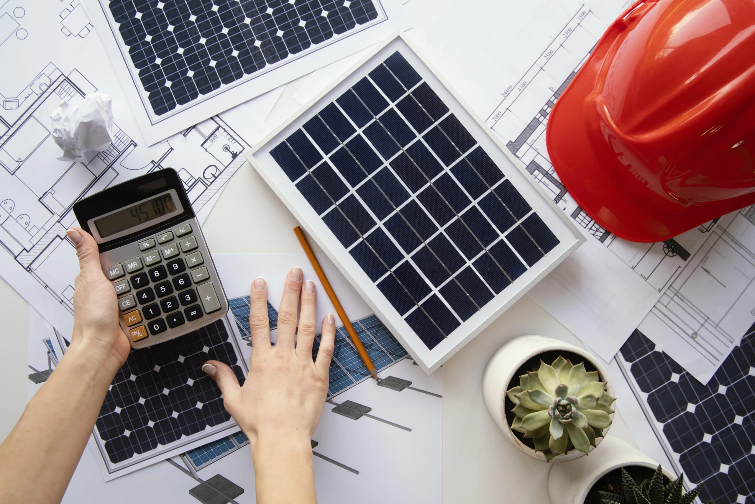 Calculator and solar panel plans on a desk with system designs, illustrating the cost comparison between exporting solar energy and storing it in a battery for maximum savings.