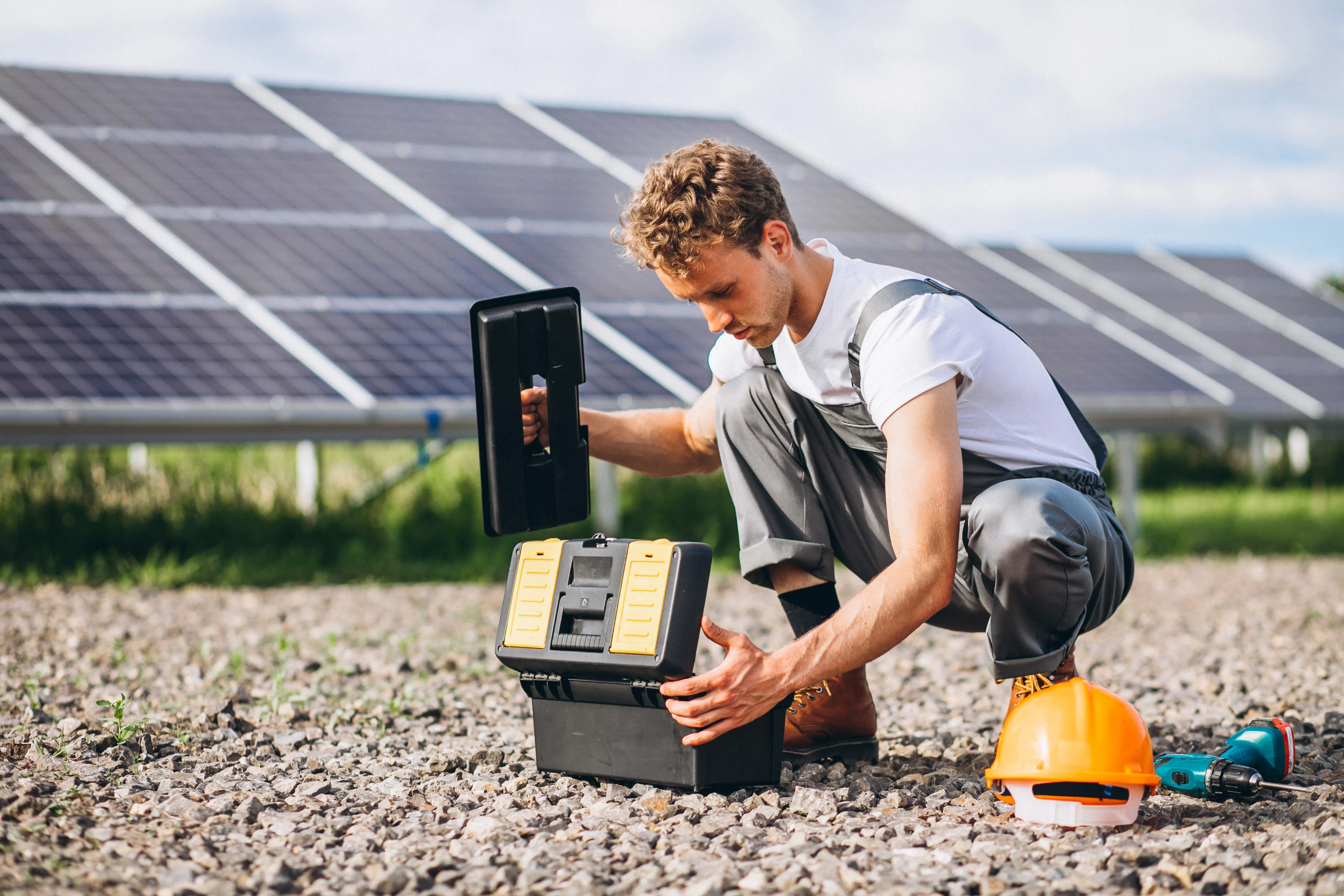 Technician working with battery equipment beside solar panels, highlighting assessment of energy storage systems for business use.