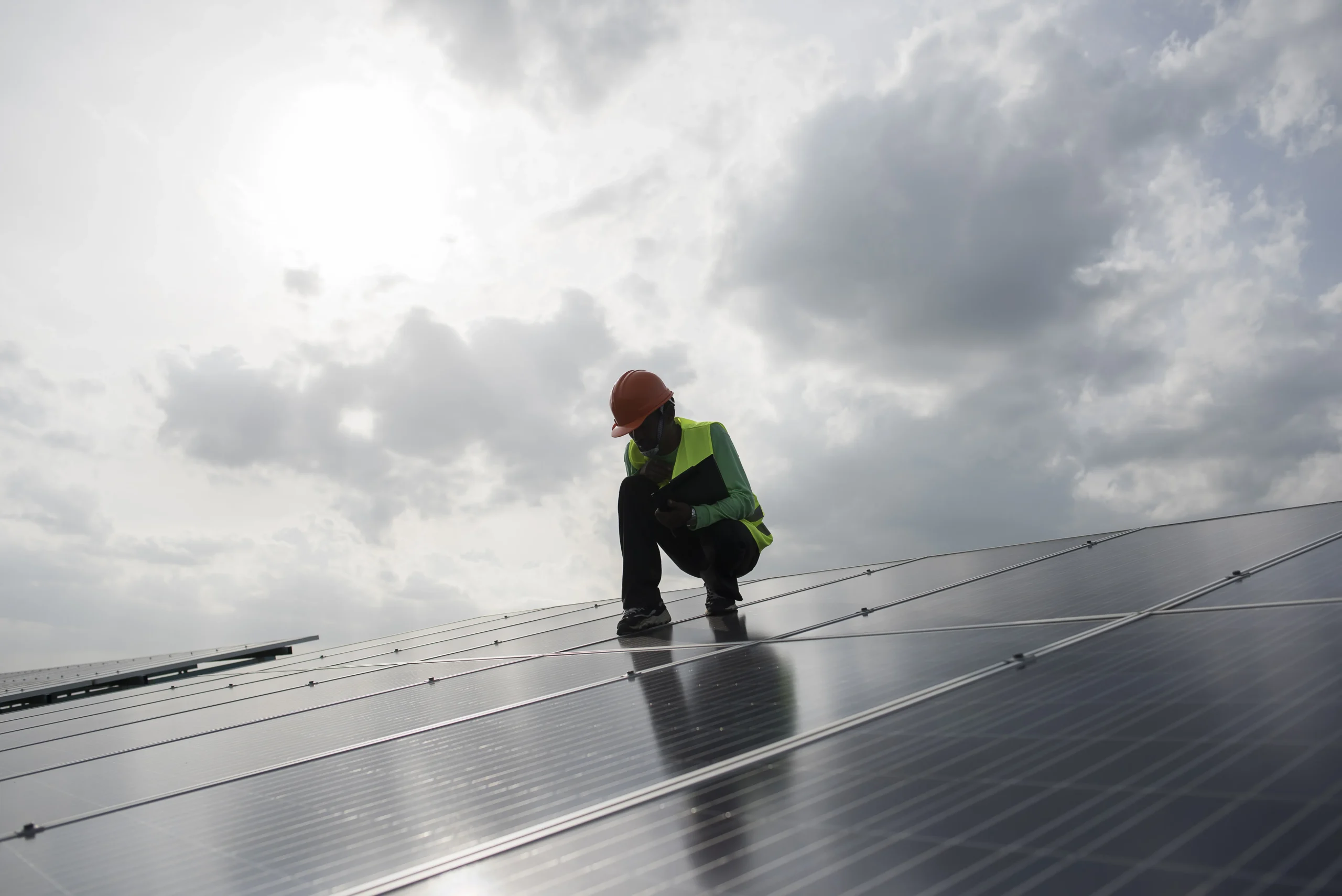 Technician working on rooftop solar panels, illustrating the process of inspecting and preparing panels for safe removal.