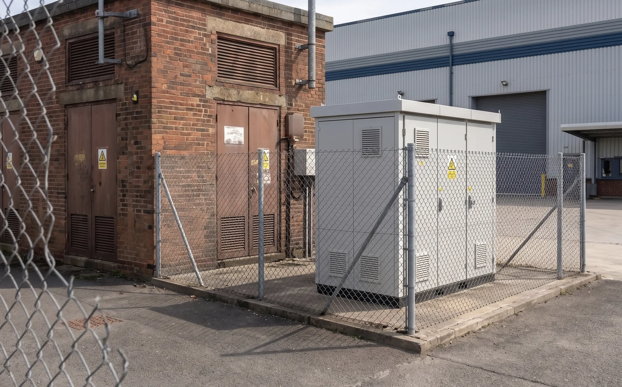Commercial battery storage cabinet beside an industrial building, illustrating standalone battery units versus modular energy storage system designs.