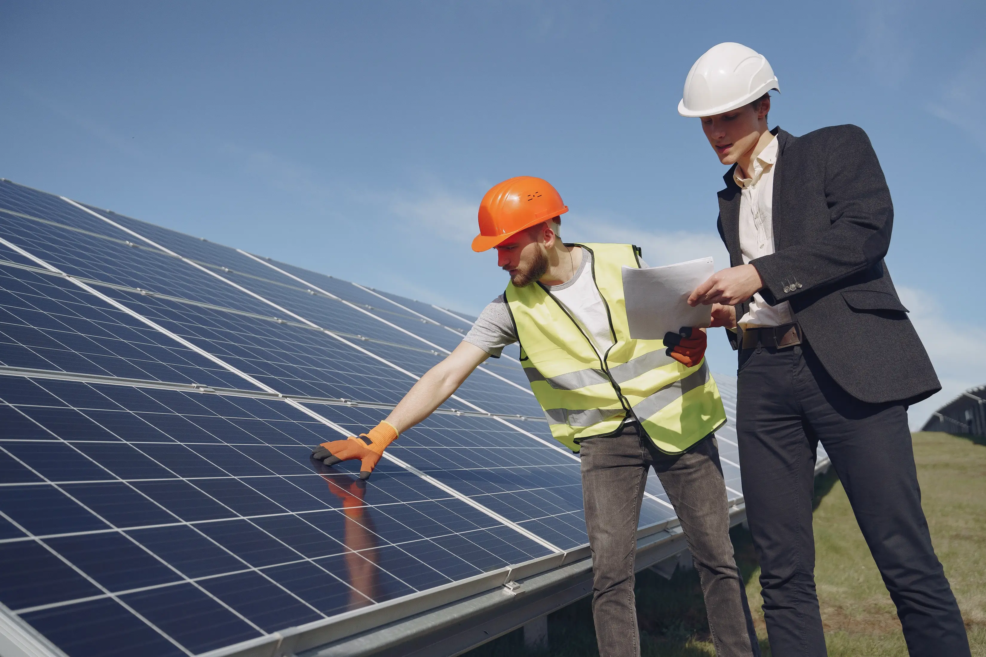 Solar installer and homeowner reviewing an existing solar array, representing the planning, system assessment, and upgrade decisions involved in expanding a solar panel setup cost-effectively.