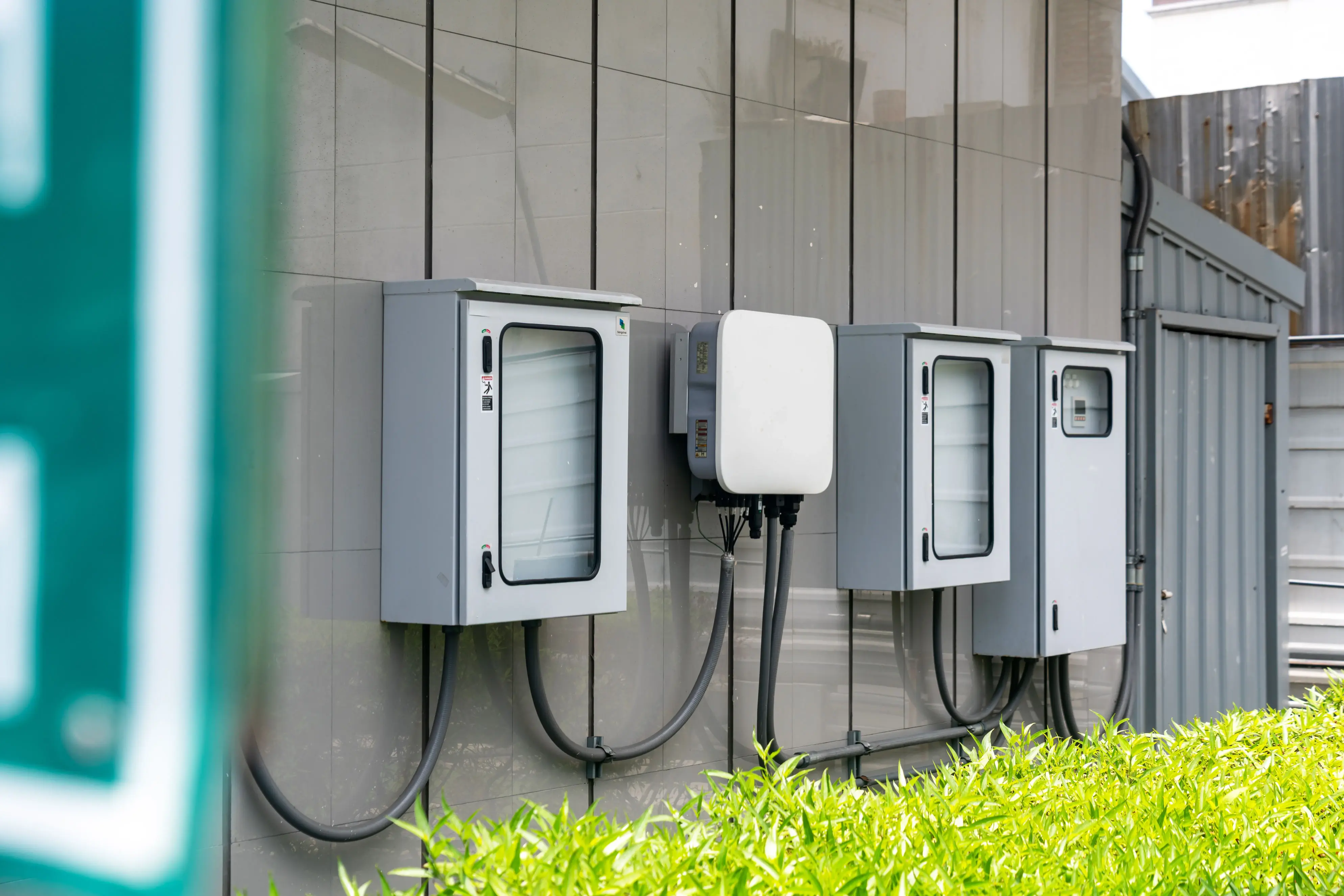 Residential solar battery storage and inverter system mounted on an exterior wall, connected to electrical control panels for home energy management and backup power.