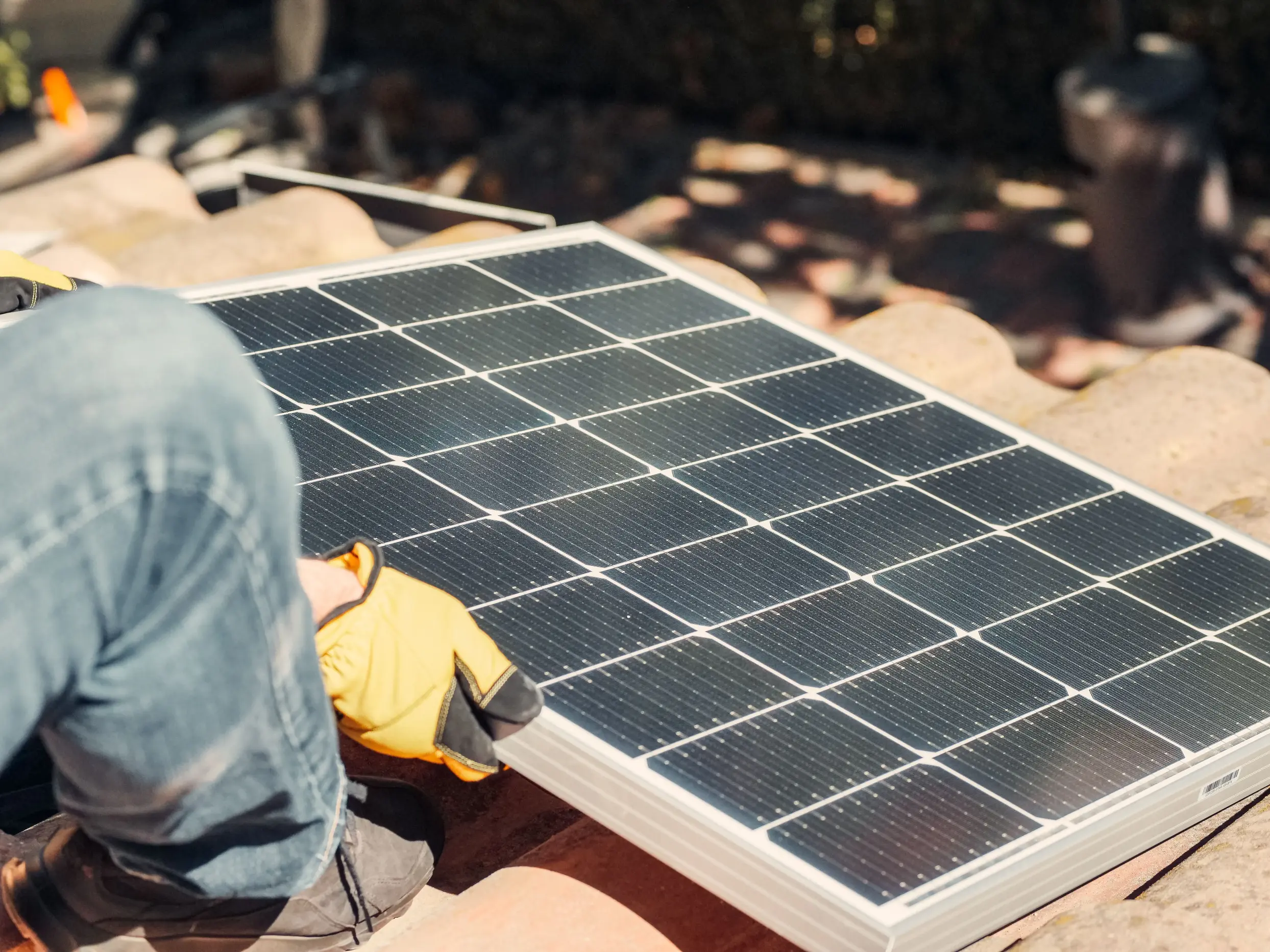 Homeowner installing a rooftop solar panel on a residential property, illustrating the relationship between solar generation, battery storage, and backup power solutions that can help maintain electricity during grid outages and blackouts.