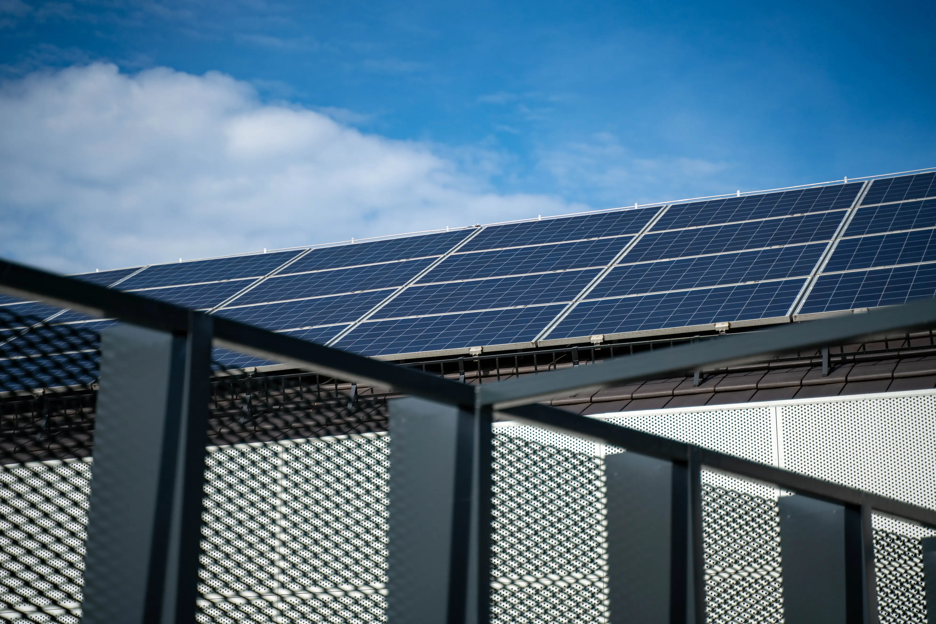 Large rooftop solar panel array installed on a commercial or multi-unit residential building, generating renewable electricity under a clear blue sky.