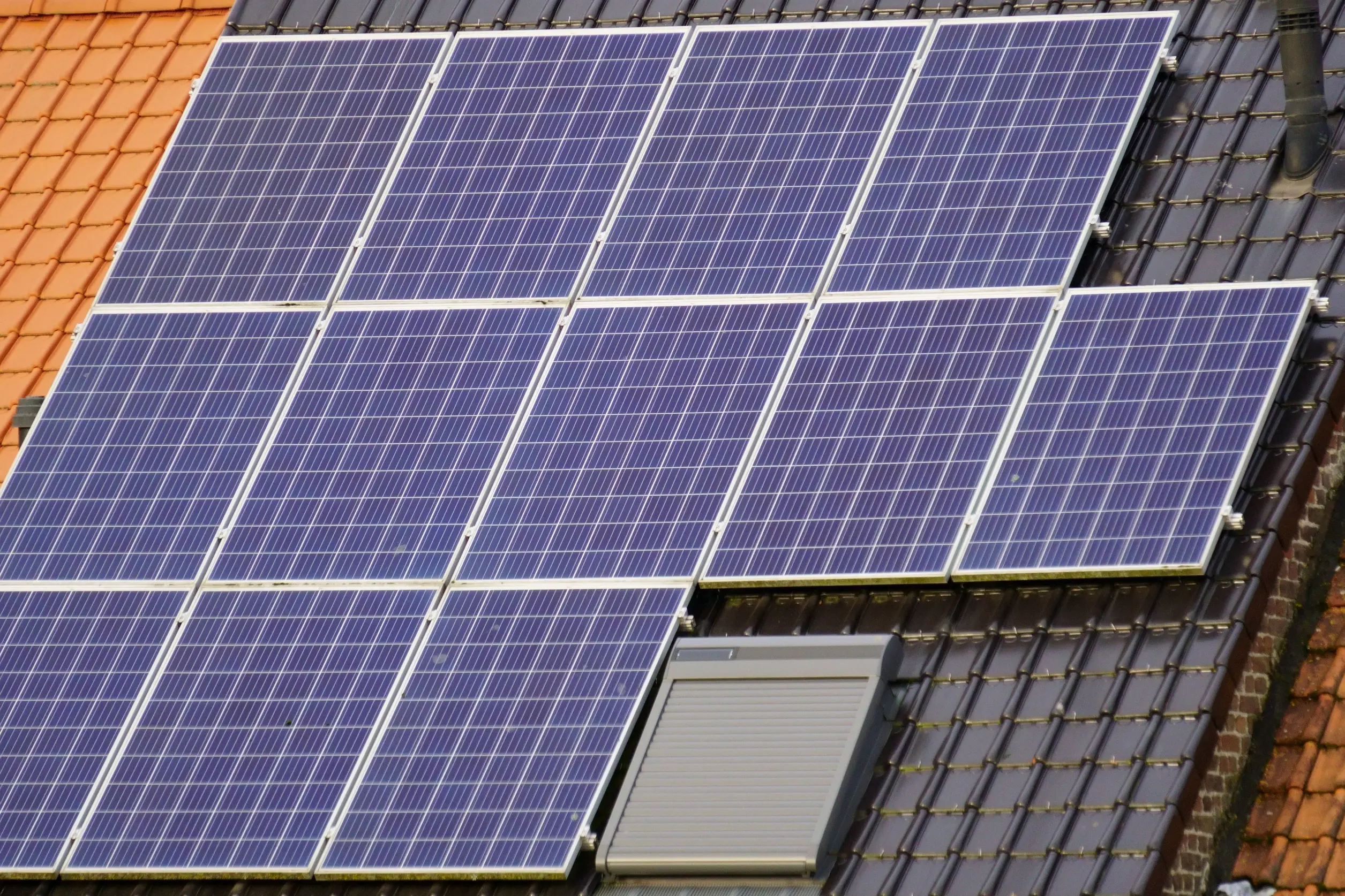 Residential rooftop solar panel installation on a tiled house, illustrating how owned solar systems can improve energy efficiency and potentially increase UK property value.