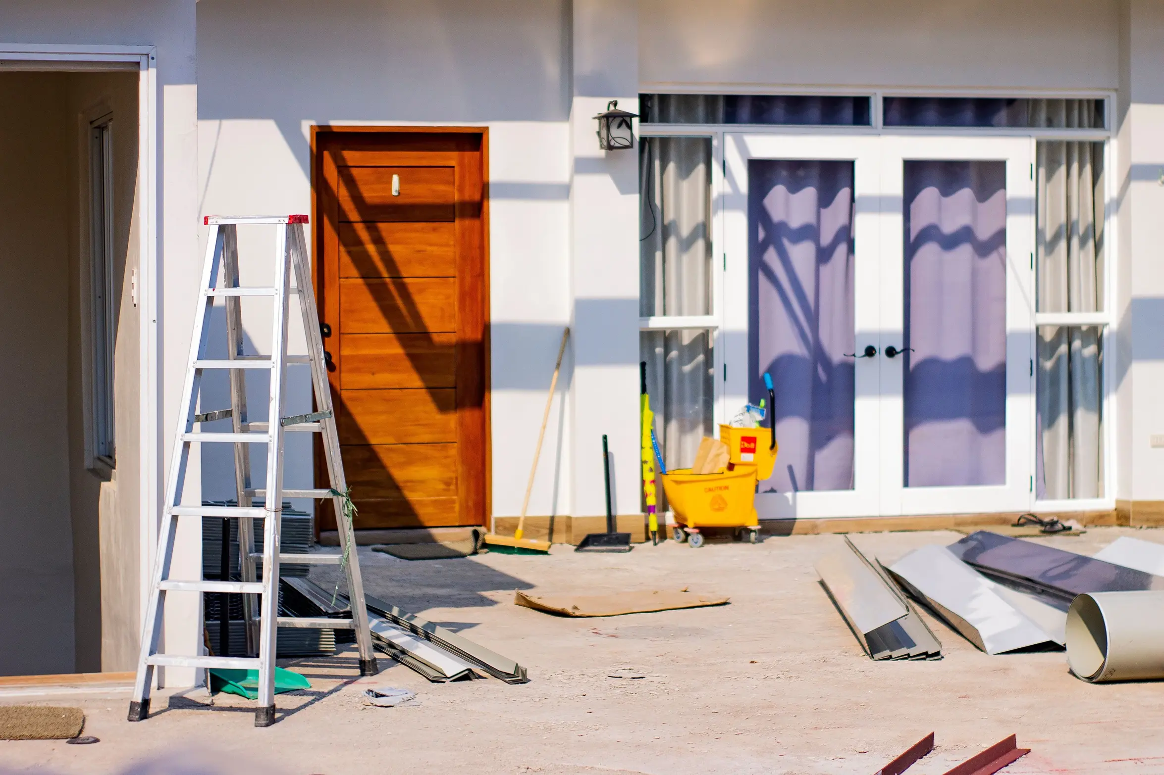 Exterior of a house undergoing renovation with a ladder, building materials, and maintenance equipment outside, representing the ideal stage to plan solar panel installation alongside renovation work.