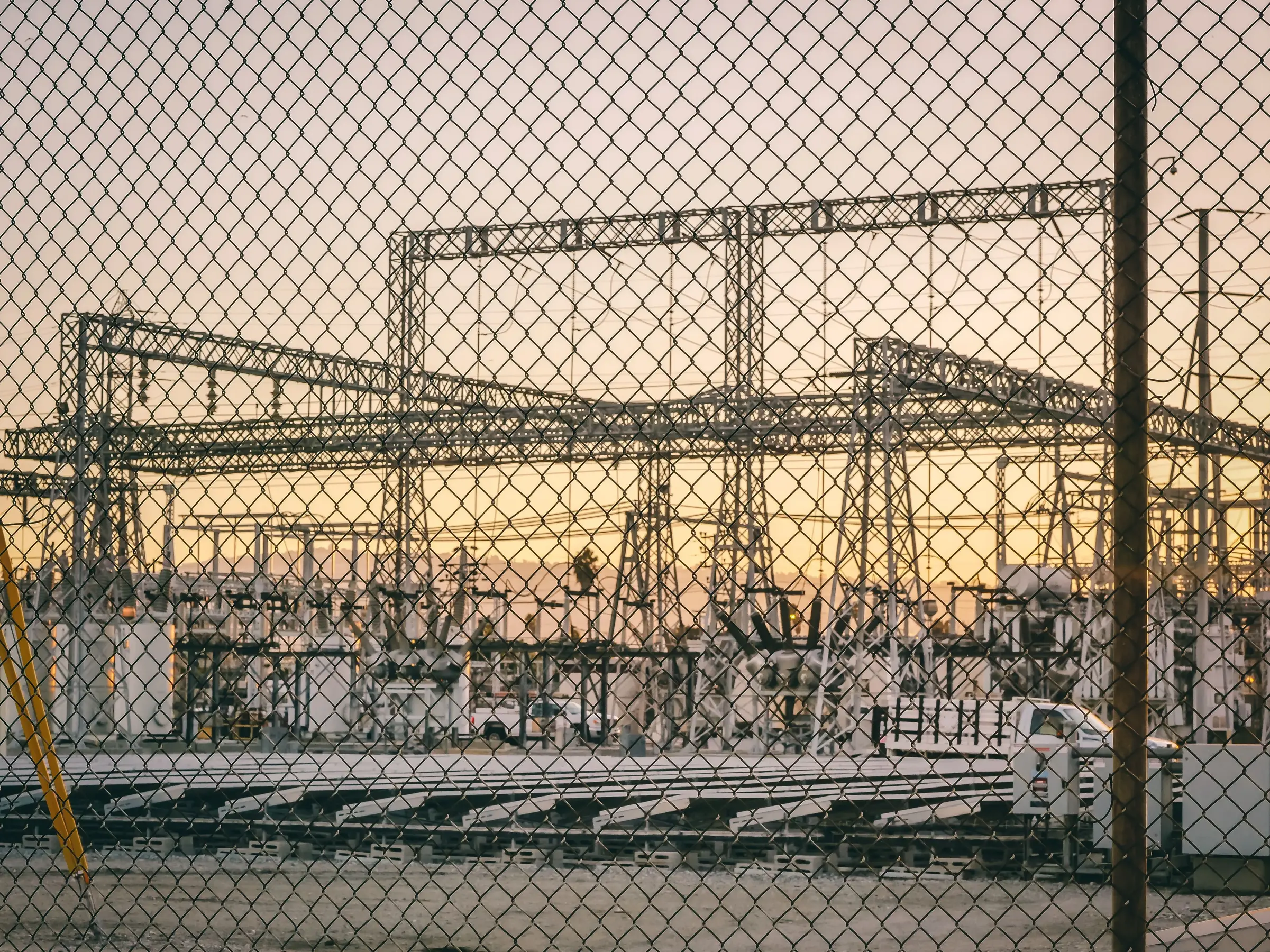 Electrical substation and transmission infrastructure behind a security fence, representing the UK's transition to a cleaner electricity grid under the Clean Power 2030 plan.