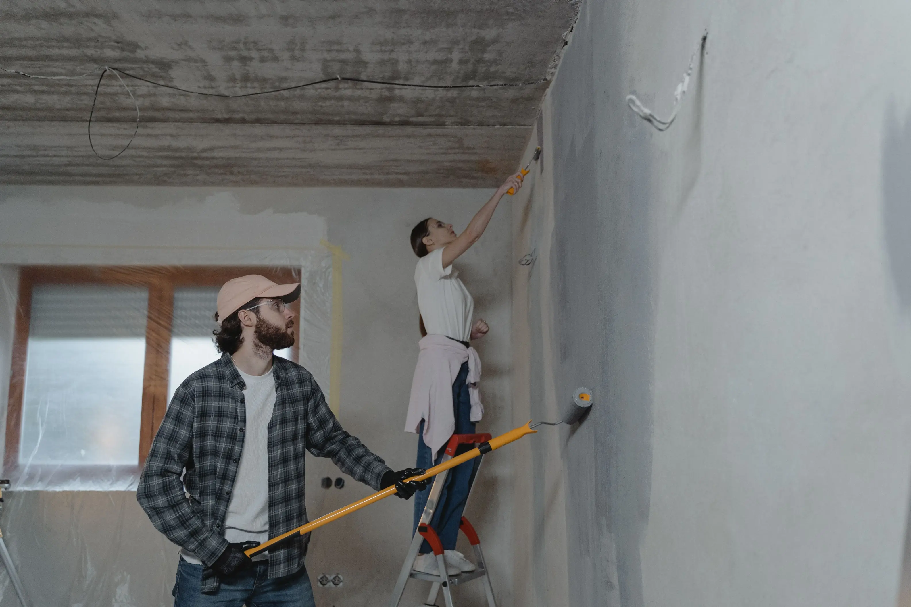 Homeowners renovating an interior room while preparing walls and ceilings, illustrating the ideal stage to plan solar panel installation alongside major building work.